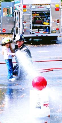Fire safety at GWL elementary Greenwood Lake Fire Department Lt. John Rader helps a student to shoot the hose and knock a ball off the can.
