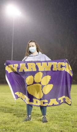 WVHS Senior Nina Lazina holds a Warwick Wildcats banner in the pouring rain during the Light The Lights tribute on Friday evening, May 8.
