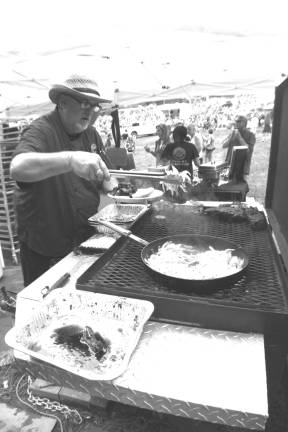 Chumley's named the best Chef Dan Lemire of Chumleys BBQ and Catering of Florida, N.Y. is shown cooking up some ribs at the fourth annual Rock, Ribs and Ridges music and food festival held last weekend at Hidden Valley Resort. Lemire attended the Culinary Institute of America and this yearís ribs were available with a variety of sauces including Root Beer, Fired Up, and Apple Garlic.The event started on Saturday and although the rains had passed they left behind milky skies and plenty of mud that organizers covered with hay spread throughout the concert grounds.