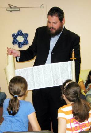 Historic Holocaust 'Kristallnacht' Torah comes to Chabad of Orange County Provided photos Rabbi Pesach Burston, director of Chabad of Orange County, displays a toy Torah as he teaches Hebrew School students what a Torah looks like inside and how it is written, in preparation for Shavuot.