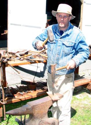 Historical Society sponsors blacksmithing class Photos by Roger Gavan Robert Schmick, director of the Historical Society of the Town of Warwick, demonstrates how holes in metal objects were made by hammering a spike on the hot metal placed over a hole in the anvil. Most of the primitive stoves and tools used in the course came from his private collection.