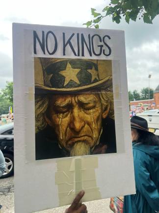 Hundreds rally in ‘No Kings Day’ protest The quote on the sign is based on lines from “Waist Deep in the Big Muddy” by Pete Seeger.
