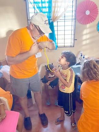 Dr. John Juliano of Warwick lets his young patient take a turn listening to “Dr. Juan’s” heart during his visit to a medical clinic set up in a village near Sosúa, in the Puerta Plata region of the Dominican Republic.