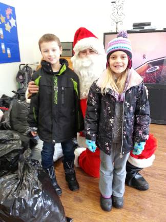 Children participate in clothing and food drive for the Alamo Community Center Rocco and Page Manno with Santa.