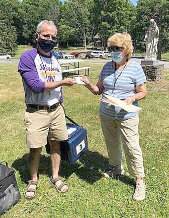 Longtime volunteer Ellie Nye, who is a Friday captain for Meals on Wheels of Warwick, presents a pin to volunteer Kevin Glover. Photos provided by Debby Briller.