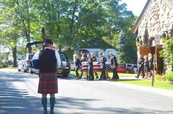 A bagpiper plays as John Rader is moved out of the church.
