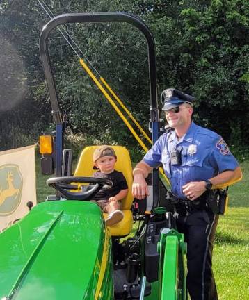 Nash Horton climbs onto a tractor with the help of his dad, Warwick Police Officer Timothy Horton.