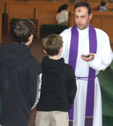 'Turn away from sin and be faithful' The Rev. Richard Marrano, parochial vicar of the Church of St. Stephen, the First Martyr, administers ashes to parishioners on Wednesday, Feb. 14.