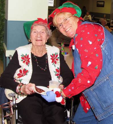 Schervier Pavilion hosts Christmas party Volunteer Pat De Negri (right) serves a couple of holiday treats to her mom, Ann Goral.