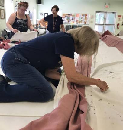 Repair Cafe seamstresses Regina Shaw, Deanne Singer and Elena Valentino work on the flag.