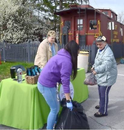 Warwick Valley Coalition Coordinator Francesca Bryson (left) holds a large garbage bag for Nydia Feldner to place unwanted medications in as Coalition member Judy Quackenbush looks on.