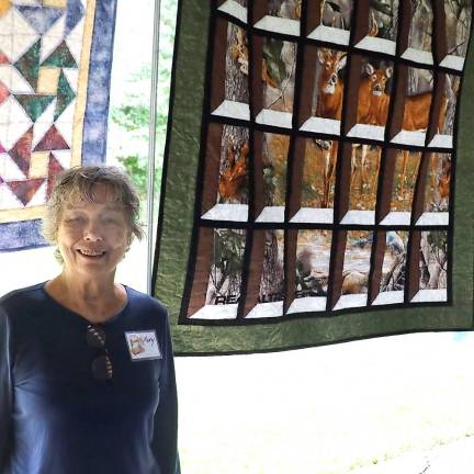 Organizer Mary Kirchoff poses in front of a unique quilt crafted by Warwick resident Diana Eschmann.