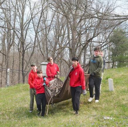 Members of Boy Scout Troop 45 carried a tarp filled with tree branches out of the Amity Cemetery on Saturday.