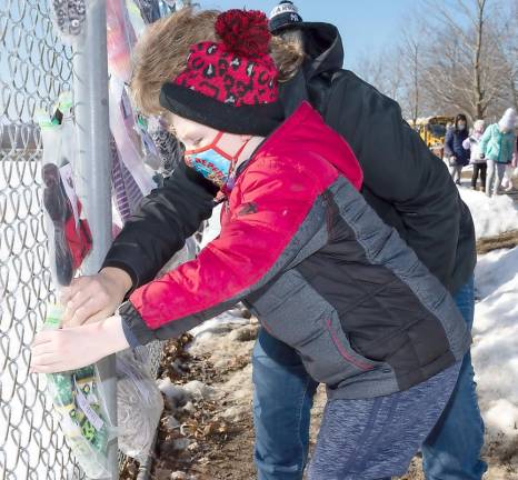 Kindergarten student Connor Leisengang hangs up a cold weather item on a fence at Pine Island Park.