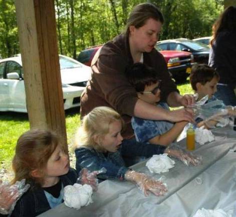 Temple celebrates joyous Lag B'Omer holiday Kindergarten teacher Elizabeth Frederick helps little ones tie-dye T-shirts at the Lag B'Omer celebration.