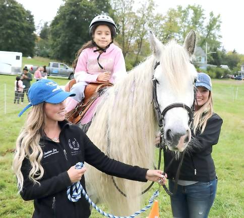Martina Cedena, 8, enjoys a ride atop one of Winslow Therapeutic Center's gentle horses led from left by Winslow staff member Stacy Lenz and volunteer Kerrian Scully.