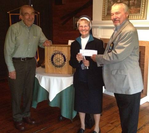 A garden grows Photo by Roger Gibboni Garden of the Child founder Sister Anna Roche accepts the organizationís 24th annual contribution from the Warwick Valley Rotary Club. Leo Kaytes, left, helped promote the start-up efforts in 1989 when he was Rotary president. Since then Warwick Rotarians have donated almost $25,000 to Garden of the Child. At right is John Buckley, Warwick Rotary president.
