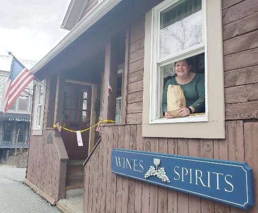 Local businesses and members of the Warwick Valley Chamber of Commerce cope with coronavirus epidemic Peck’s Wine and Spirits manager Corrine Iurato servers a customer from a sidewalk facing window.