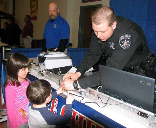 Seventh annual Warwick Valley EXPO 2014 welcomes more than 1,000 visitors Officers from the Orange County SheriffþÄôs Office were on hand offering parents an opportunity to participate in the agencyþÄôs þÄúSafe ChildþÄù program. Investigator B. Manning looks on as Officer J. Morales takes digital fingerprints of five year old Heather Day and Riley Butler.