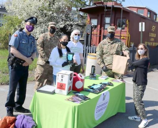 The annual “pill drop” organized by the Warwick Valley Coalition in cooperation with the Warwick Police Department and the Drug Enforcement Administration collected approximately 150 pounds of unused prescription and over-the-counter medications. Warwick business owner Jenny Altman (right) hands over a bag of unused prescriptions to volunteers from the Warwick Valley Coalition, the Warwick Police Department and the National Guard Counter Drug Task Force.