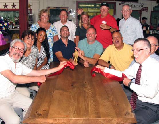 Pennings installs new live-edge Rootstock tables in its pub Photo by Roger Gavan On Aug. 5, public and business officials joined Steve and Jill Pennings and Rootstock owners Chris Gehrlein and Chris Pape for a ribbon cutting to celebrate the new furnishings. Seated clockwise from left, Mayor Michael Newhard, Warwick Valley Chamber of Commerce past President Sherry Bukovcan, Diandre Foy, her fianc‡©e and Rootstock co-owner Chris Gehrlein, his partner Chris Pape, chamber board member Wayne Paterson, chamber President Doug Stage and Town of Warwick Supervisor Michael Sweeton. Standing from left, Dale and Sarge Gehrlein, Jill and Steve Pennings and Michael Johndrow, executive director of the Warwick chamber.