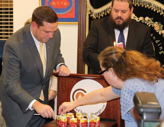 'How do we respond to baseless hatred? Wanton love' Candles were lit at the Chabad in Chester, in the Jewish tradition, with county Executive Steve Neuhaus (left), Rabbi Pesach Burston, and Sherri Eccelston of Johnson, N.Y.(Photo courtesy of the Orange County Executive)