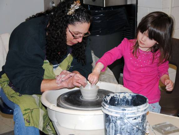 Empty Bowls project raises $35,000 Local potter Sharon Galbraith of East Ridge Pottery teaches a young girl how to make a pottery bowl.