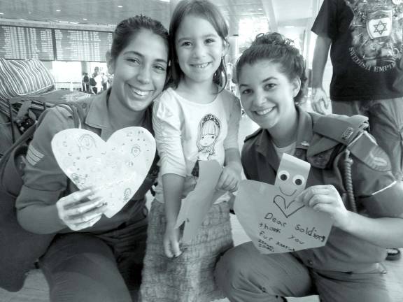 Good deeds, near and far Rivkah Burston, 5, of Monroe, gives out her heart-shaped card to a soldier in Israel is Tel Aviv. She also helps give out cards that other campers designed.