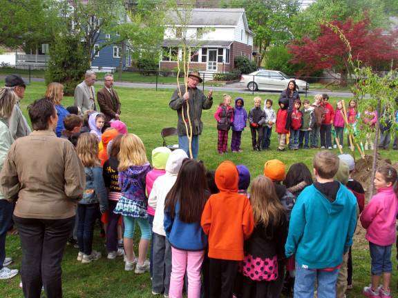 Warwick school children help plant a tree for Arbor Day Guest speaker Daniel Mack, a rustic furniture maker and artist, compared the way a tree grows with life in general and then delighted the children with a poem, ìTalking Trees.î