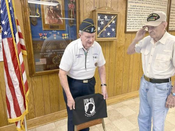 Warwick brothers and World War II veterans Don and Warren McFarland will recognize American prisoners of war and those missing in action with a POW/MIA Empty Chair during the Sept. 8 flag retirement event at American Legion Post 214 in Warwick. The empty chair, displayed at all official American Legion meetings, is a physical reminder of the thousands of Americans still unaccounted for from all wars and conflicts involving America. Warren McFarland, 98, salutes while Don McFarland, soon to celebrate his 96th birthday, places a symbolic cover on the POW/MIA chair. Photo by Stan Martin.