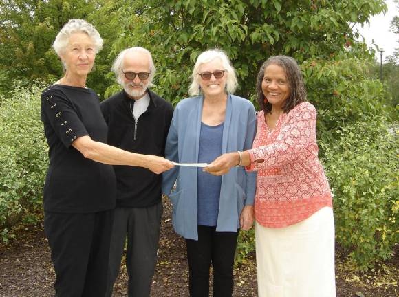 Mary Makofske of Sustainable Warwick passes a check to Beverly Braxton of Family Central as new heat pump owners Jerome and Paula Spector watch.