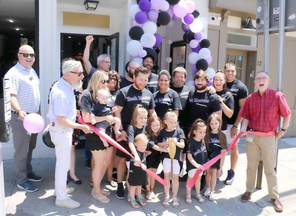 On Wednesday, June 30, Town of Warwick Supervisor Michael Sweeton (right), Mayor Michael Newhard (left) and members of the Warwick Valley Chamber of Commerce joined owner Brian Monahan, his family and staff to celebrate the opening of the company’s new office at 16 Main St. in the Village of Warwick. Monahan’s granddaughter Elliana Herrmann, 8, had the honor of cutting the ribbon. Photo by Roger Gavan.