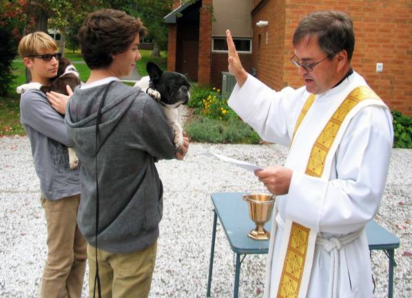 Blessed are the faithful St. Stephenís Pastor, the Rev. Michael McLoughlin, blesses "Billy," a French bulldog owned by Jared Silbernagel, as Harrison Dempster (left), holding "Lewis," a Springer Spaniel, awaits his turn.