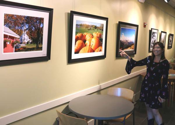 Photo by Roger Gavan Photographer Susie Schmieder points to several photographs of local scenes in her &quot;Everywhere&quot; exhibit now on display through July at the Albert Wisner Public Library.