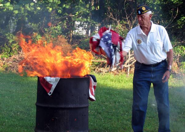 Warwick’s American Legion conducts flag disposal ceremony Jim Culligan keeps a safe distance from the fire as he tosses flags into the flames.