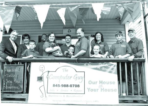 Kevin Brand, flanked by Mayor Michael Newhard and Warwick Valley Chamber of Commerce President Sherry Bukovcan (far left) and Town of Warwick Supervisor Michael Sweeton (far right) and surrounded by family and staff, cuts the ribbon during the four-year anniversary ceremony of &#xec;The Computer Guy,&#xee; at 17 West Street in the Village of Warwick.