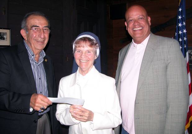 Rotarians support Garden of Child with 23 consecutive yearly donations Garden of the Child founder Sister Anna Roche accepts the organizationís 23nd annual contribution from the Warwick Valley Rotary Club. Leo Kaytes, left, helped promote the start-up efforts in 1989 when he was Rotary president. Since then Warwick Rotarians have donated almost $25,000 to Garden of the Child. At right is Wayne Patterson, Rotary Warwick Rotary president. Photo by Stan Martin