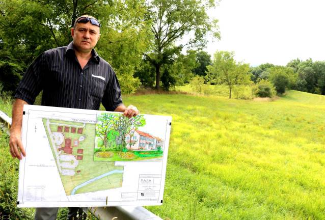 Developer Stephen Kitar poses with his plan and an artist rendition of the proposed inn outside the almost 10 acre property along West Street identified by the prominent formation known as Pulpit Rock.
