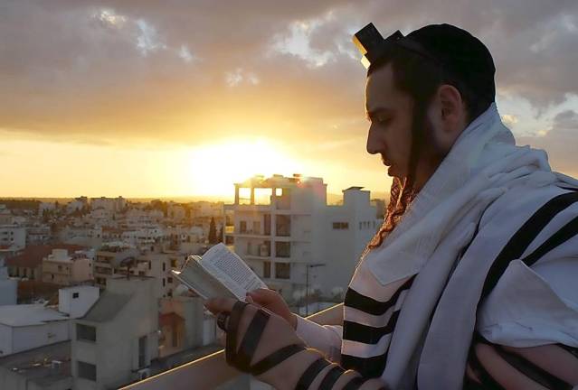 Shloime Zionce, donned in religious Tallit and Tefilin, praying on a rooftop In Larnaca, Cyprus.