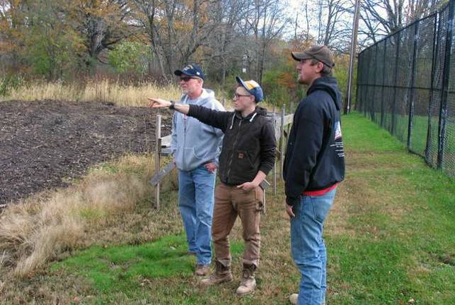 Enhancing the community experience Photos by Roger Gavan Project Knomad co-Facilitator Innis Sampson (center) explains the Perma-Culture Community Garden Initiative plans to her brother Matt Sampson (left) and her father, Jim Sampson. (right).