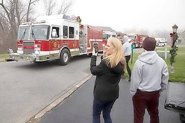 Hillary Hansen, pictured here with her family, takes cellphone video of Santa Claus riding along with the Pine Island Fire Department as parents and kids came out of their homes to see him on Saturday, Dec. 12. Photos by Robert G. Breese.