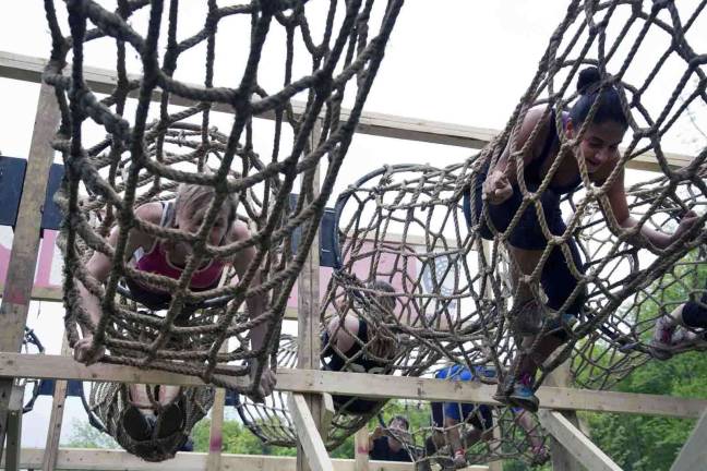 Thousands participate in Warrior Dash at Warwick Day Camp Photo by Robert G. Breese Participants in the Warrior Dash in Warwick climb through a net obstacle on Saturday.