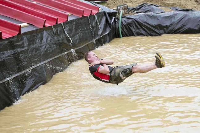 Thousands participate in Warrior Dash at Warwick Day Camp Photo by Robert G. Breese A man makes his way off the slide and into a four-foot deep pool of muddy water during the Warrior Dash in Warwick on Saturday.