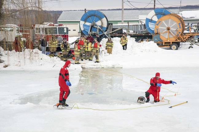 Preparing for when hell freezes over Pine Island firefighters standby on the shoreline while volunteers Scott Hansen (right) and Matthew Sampson use chain saws to cut a hole in the 16-inch deep ice to simulate someone falling through the ice.