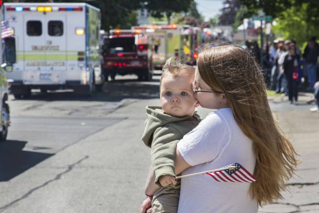 Warwick honors its veterans Photo by Robert G. Breese A young patriot holds an American flag while intently watching the Memorial Day Parade from the comfort of his mother's arms along Oakland Avenue in Warwick on Monday morning.