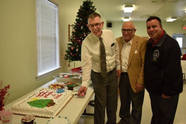 Photos provided by Jean Corbi Ciappa Warwick Town Supervisor Michael Sweeton cuts the cake at the Friendly Visitor Program Volunteer/Appreciation Holiday party as FVP Board Chairman Vince Copello and Assemblyman Karl Brabence look on.