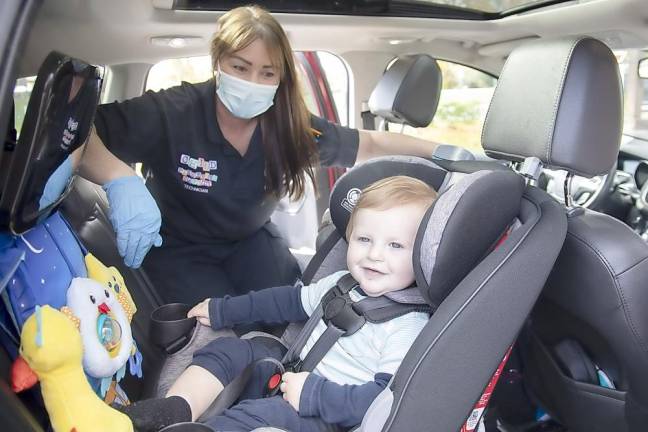Brooks Meacham takes his newly installed car seat for a test drive while Warwick Police Officer Amie McGrady looks on during the car seat safety check event at ShopRite Shopping Center in Warwick on Oct. 24.