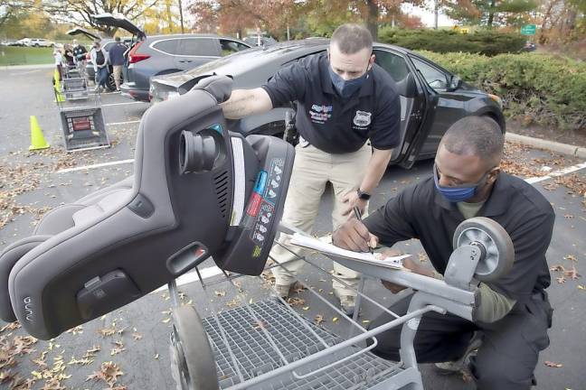 Warwick Police Officer Steve Pascal and Spring Valley Police Officer Quacy Evelyn doing a car seat safety examination at ShopRite Shopping Center in Warwick on Oct. 24.