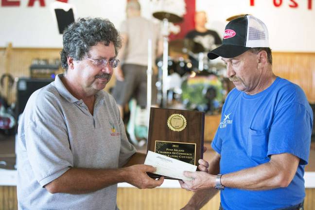 The sweet taste of victory Photo by Robert G. Breese Russell Kowal (left) of the Pine Island Chamber of Commerce hands a plaque and $100 check to winner Raymond Wesolowski of Westtown who was the winner of the annual onion eating contest held during the Pine Island Summerfest last weekend.