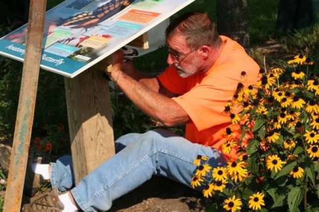 Paul Hudler works on the butterfly signs for the Pine Island Park Butterfly Garden.